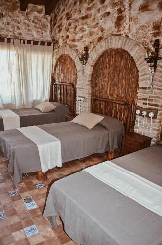 ColungoAntiguo Rincón的一间卧室设有三张床和砖墙