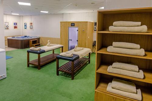 金马利奥特Tolip Family Club Borg El Arab的书架上配有几张床的客房,铺有绿色地毯