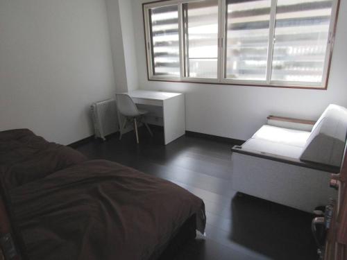 汤泽町Yuzawa Condo 一棟貸 貴重な駐車場2台無料的一间卧室配有一张床、一张书桌和一个窗户。