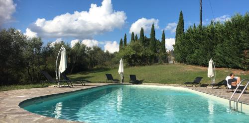 巴尔贝里诺瓦尔德尔萨Farmhouse B&B Il Paretaio的一个带椅子和白色遮阳伞的游泳池