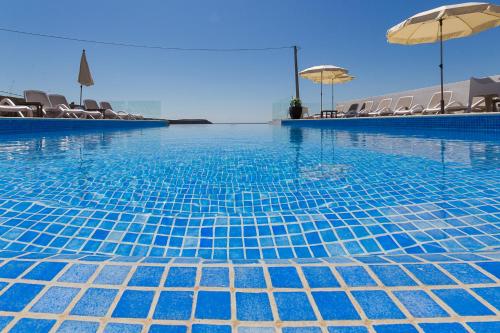 萨格里什马雷塔海滩 - 精品住宿&早餐酒店的一个带椅子和遮阳伞的蓝色游泳池