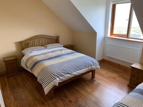 伊尼希尔岛Cliffs of Moher View的一间卧室配有带条纹棉被的床和窗户