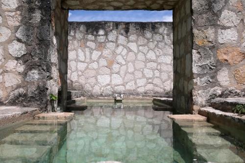 科巴Coqui Coqui Papholchac Coba Residence & Spa的石墙前的水池