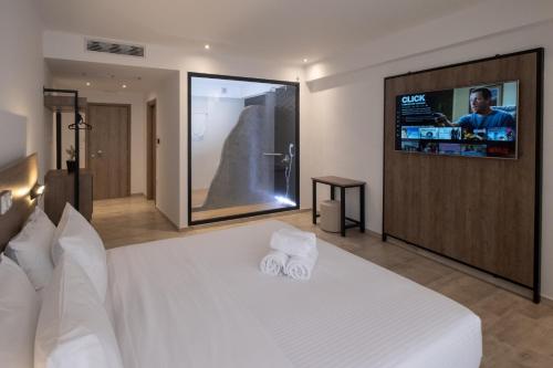 西洛卡特伦Sette Suites & Rooms - Adults Only的卧室配有白色的床,墙上配有电视