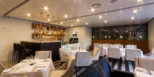 皮里港艾伦酒店 的一间设有白色桌椅的餐厅和一间酒吧
