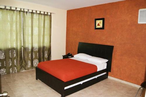 萨利纳斯马尔凡图II号酒店的一间卧室配有一张带橙色墙壁和窗户的床