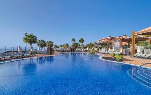 科斯塔卡玛H10汀达亚旅馆的棕榈树和椅子的度假村的大型游泳池
