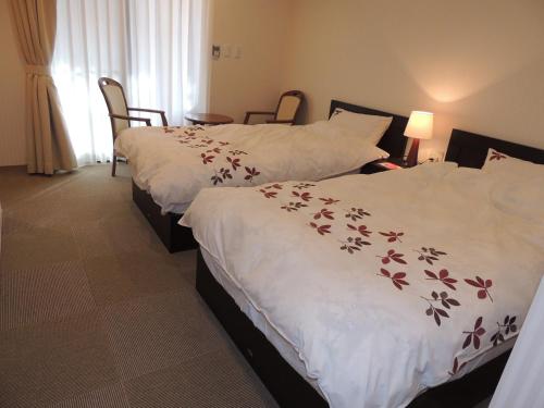 轻井泽海奇安住宿加早餐酒店的两张位于酒店客房的床,配有白色的鲜花床单