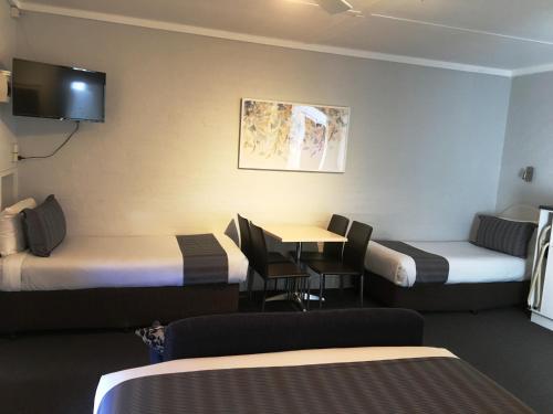 海伊Nicholas Royal Motel - No Pets Allowed的酒店客房设有两张床和一张桌子。