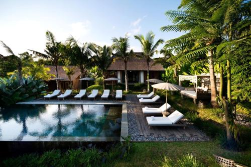 坎古卡拉帕瑜伽精品度假村 的一个带躺椅和遮阳伞的游泳池的度假酒店