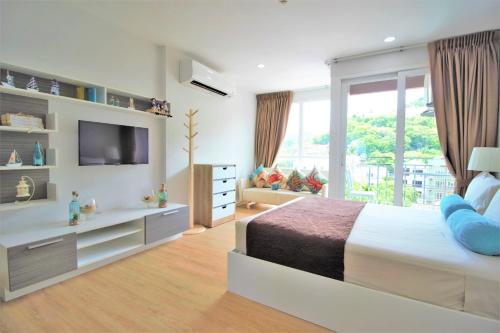 卡塔海滩Ozone Condotel Kata Beach by PHR的一间卧室配有一张大床和电视