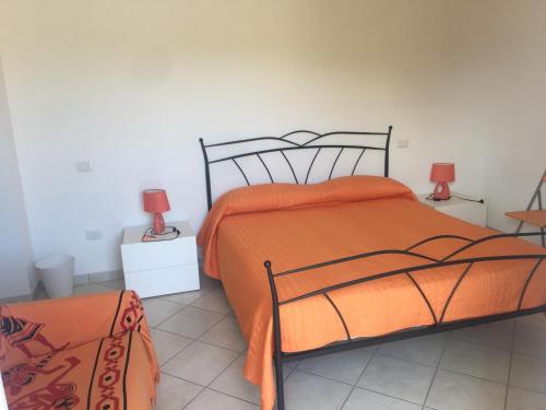 马里纳迪马萨B&B Gigi’的一间卧室配有一张带橙色棉被和两盏灯的床。