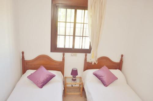 阿尔加尔San Nicolás的配有两张紫色枕头的宿舍间内的床铺