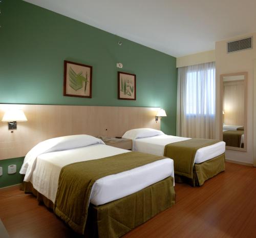 萨尔瓦多Rede Concept - Hotel Salvador的绿墙旅馆客房的两张床