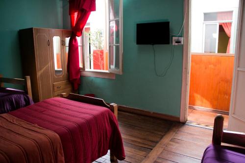 瓦尔帕莱索Hostal Tricontinental的一间卧室配有一张床铺,床上铺有红色毯子