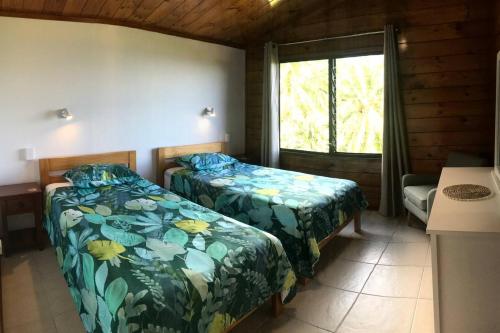 拉罗汤加Pacific views, tranquil location, extra large home, Navy House 1的一间设有两张床的卧室和位于小屋的窗户