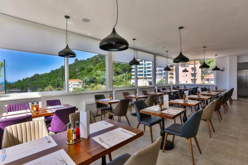 布德瓦Hotel Lusso Mare by Aycon的餐厅设有桌椅和大窗户。