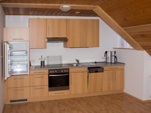 茵特斯托德皮希勒旅馆的厨房配有木制橱柜和冰箱。