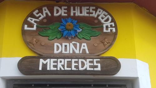 JuayúaHostal Doña Mercedes的花朵蓝色的建筑的侧面标志