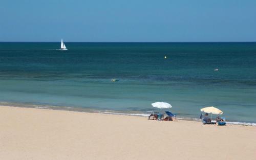 德尼亚Denia Playa I的海滩上设有椅子和遮阳伞,还有大海
