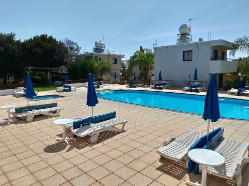 普罗塔拉斯马里科斯塔公寓酒店的一个带桌椅和遮阳伞的游泳池