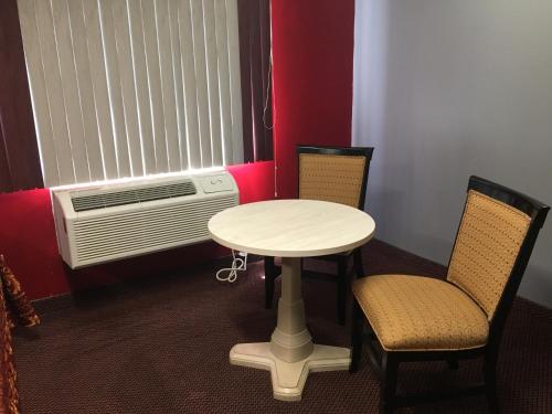 阿布西肯旅程终点汽车旅馆的客房配有桌子、两把椅子和风扇