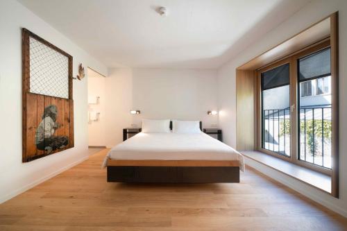 巴塞尔SET Hotel.Residence by Teufelhof Basel的一间卧室设有一张床和一个大窗户