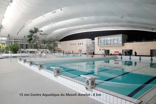 VémarsCharmant F2 à Vémars- Parc Astérix - Mer de Sable - Villepinte - Aéroport CDG的大型建筑中的大型游泳池