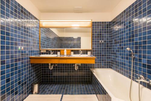 布鲁日Vintage Duplex in Bruges的蓝色瓷砖浴室设有浴缸和镜子
