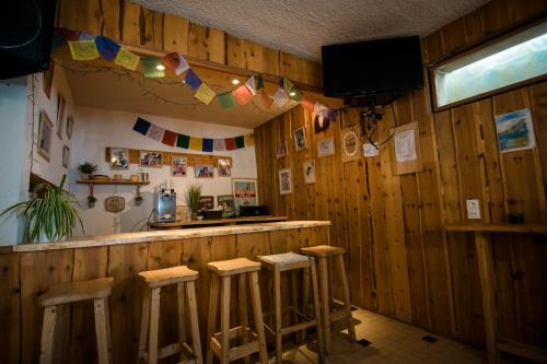 蒙乃第耶-勒潘GITE LES GUIBERTES的餐厅内的酒吧,设有木墙和凳子