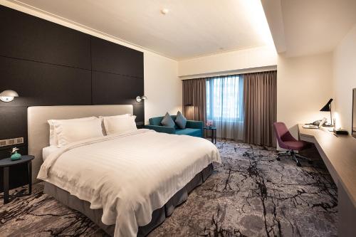 新竹新竹福華大飯店的酒店客房,配有一张床和一张蓝色椅子