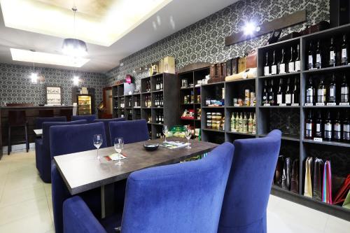 卡普利采科罗娜酒店的餐厅设有蓝色的椅子、桌子和葡萄酒瓶