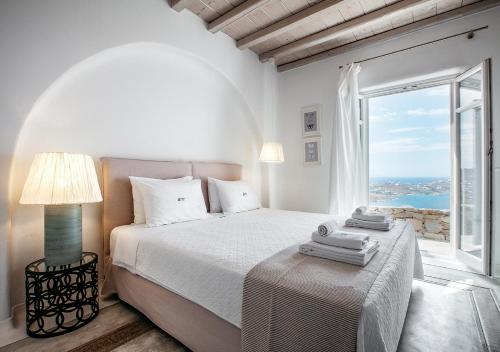 圣爱奥尼斯米科诺斯Diana Villa Mykonos的白色的卧室设有床和大窗户