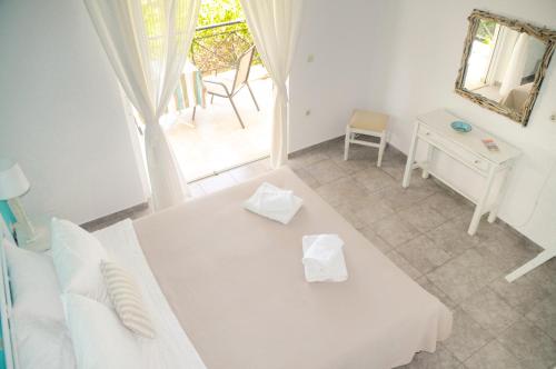 鲁维斯Heracles Guesthouse的白色的客房配有床、桌子和镜子