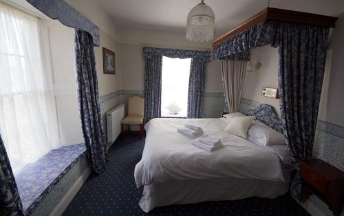 彭赞斯联盟酒店的一间卧室配有一张带蓝色窗帘的大床