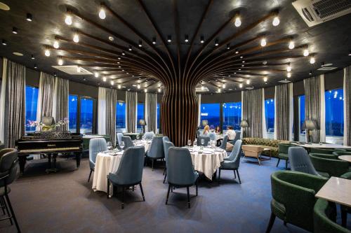 第比利斯Hotel Adamo的一间带桌椅和三角钢琴的餐厅