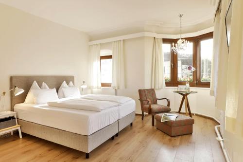 埃布斯Unterwirt - Das kleine Gourmethotel的卧室配有一张白色大床和一把椅子