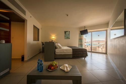 埃拉特Neptune Eilat By Dan Hotels的酒店客房,配有一张床和一张桌子,还有一碗水果
