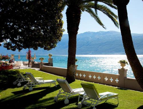 加尔尼亚诺茱莉亚别墅酒店的靠近水边的一排草坪椅和棕榈树