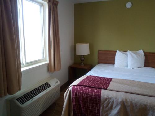 黑泽尔伍德Welcome Suites Hazelwood Extended Stay Hotel的一间卧室配有一张带窗户和散热器的床