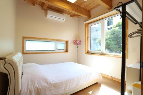 济州市济州湖膳宿度假屋的卧室配有白色的床和2扇窗户。