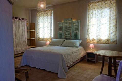 VignaleLocanda degli Ultimi的一间卧室设有床、两个窗户和一张桌子
