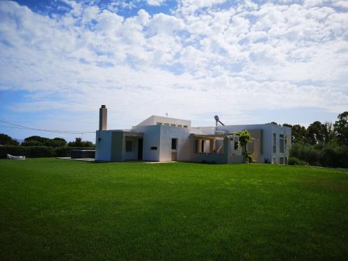 马斯蒂查里Villa Leonidas的前面有绿色草坪的白色房子