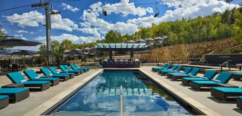 斯诺马斯村维瑟罗伊斯诺马斯酒店的一个带蓝色躺椅的游泳池和一个游泳池