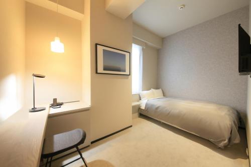 东京东京中心酒店的一间卧室配有一张床、一张书桌和一台电视。
