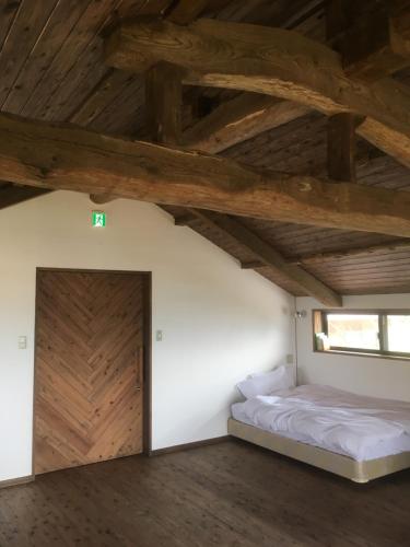 南阿苏村SOCKET的一间卧室设有一张床和木制天花板