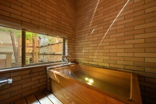 天童市修哈库太阿祖马索酒店的砖墙客房 - 带一个浴缸,设有窗户