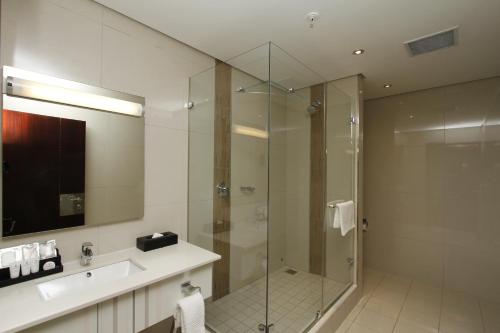德班乌姆赫兰加海岸酒店及会议中心的一间带玻璃淋浴和水槽的浴室
