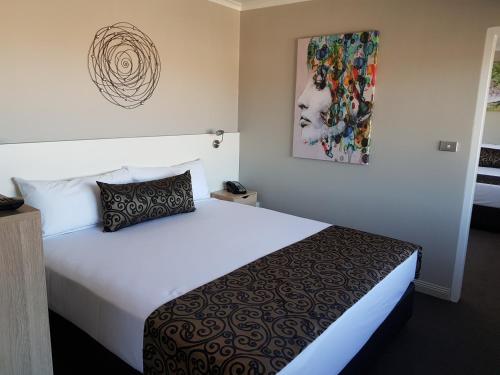 伯尔尼博尼中心联排酒店的酒店客房设有一张床,墙上挂有绘画作品