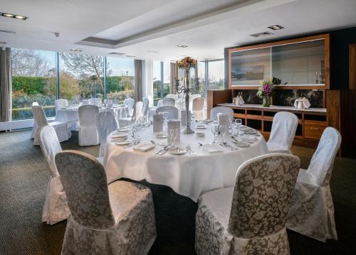 Moyvally莫伊谷高尔夫度假酒店的用餐室配有带白色椅子和桌子的桌子